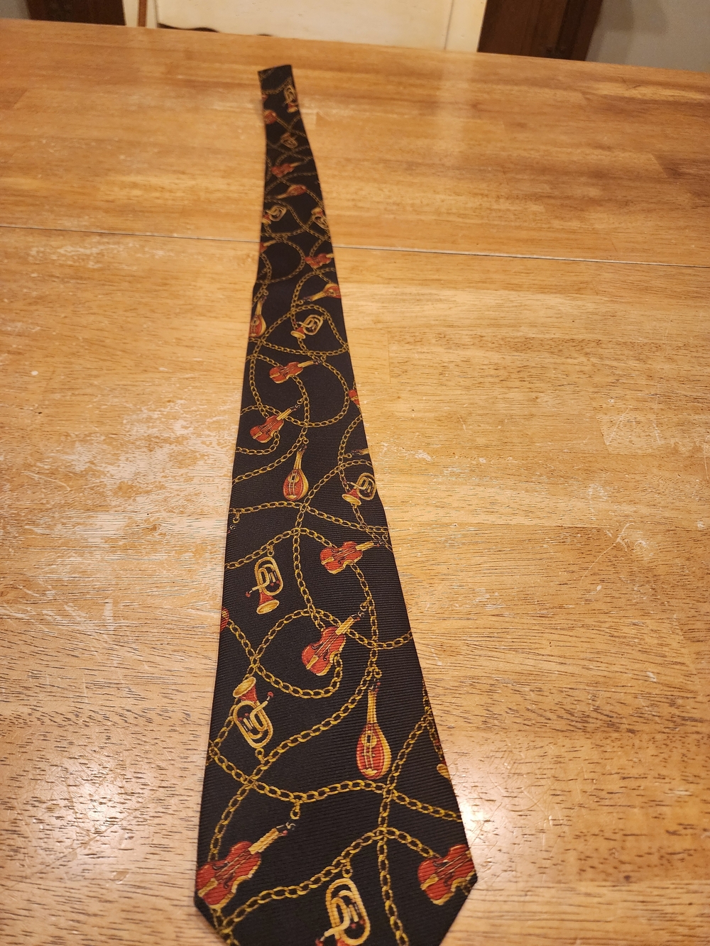 Chanel black silk necktie featuring gold chain-link and musical/brass instrument